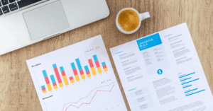 business reports with finance figures on top of desk next to laptop and coffee mug